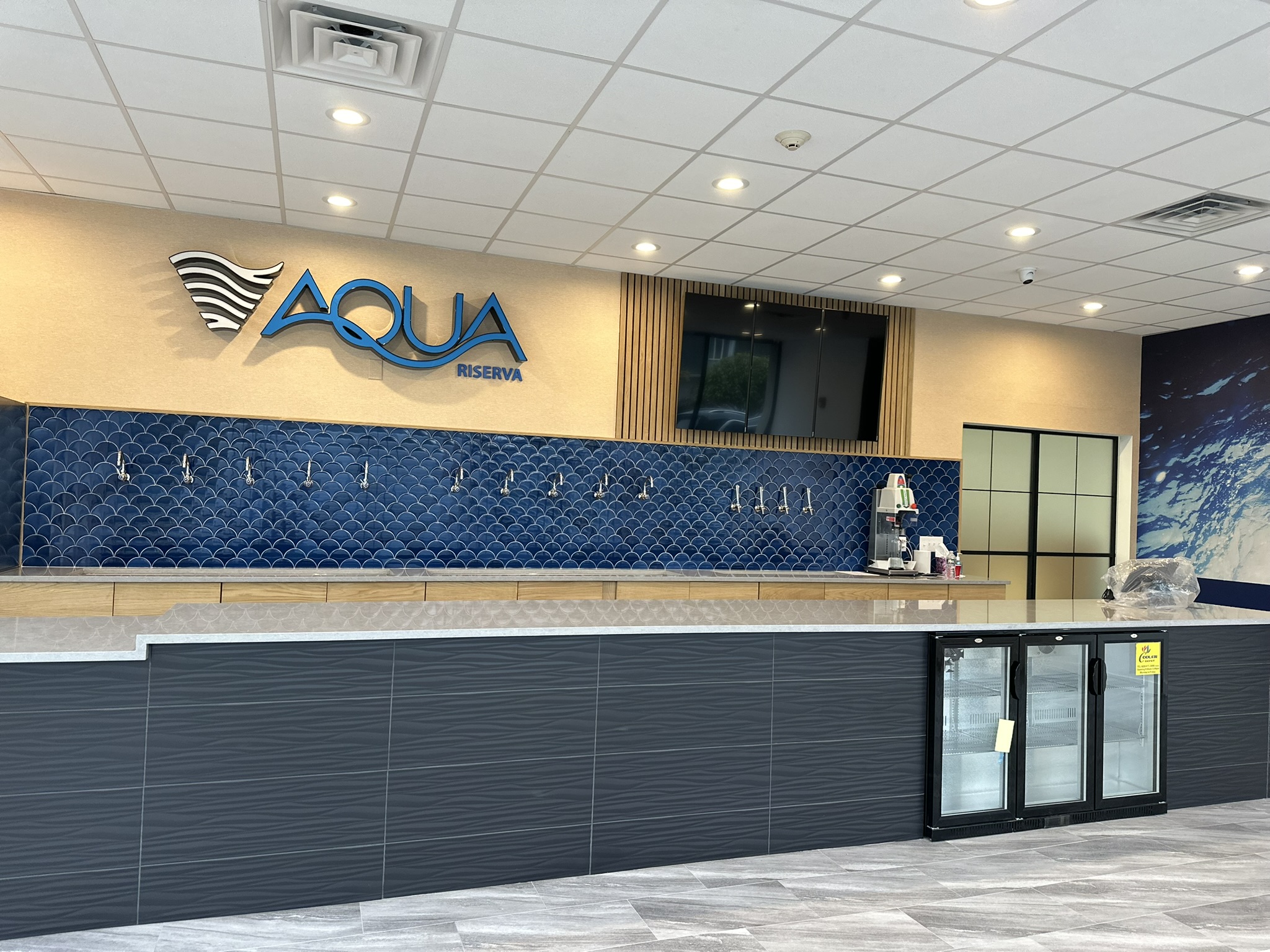 Aqua Riserva refill counter in Hawthorne, NJ, with blue fish-scale tile and branded signage