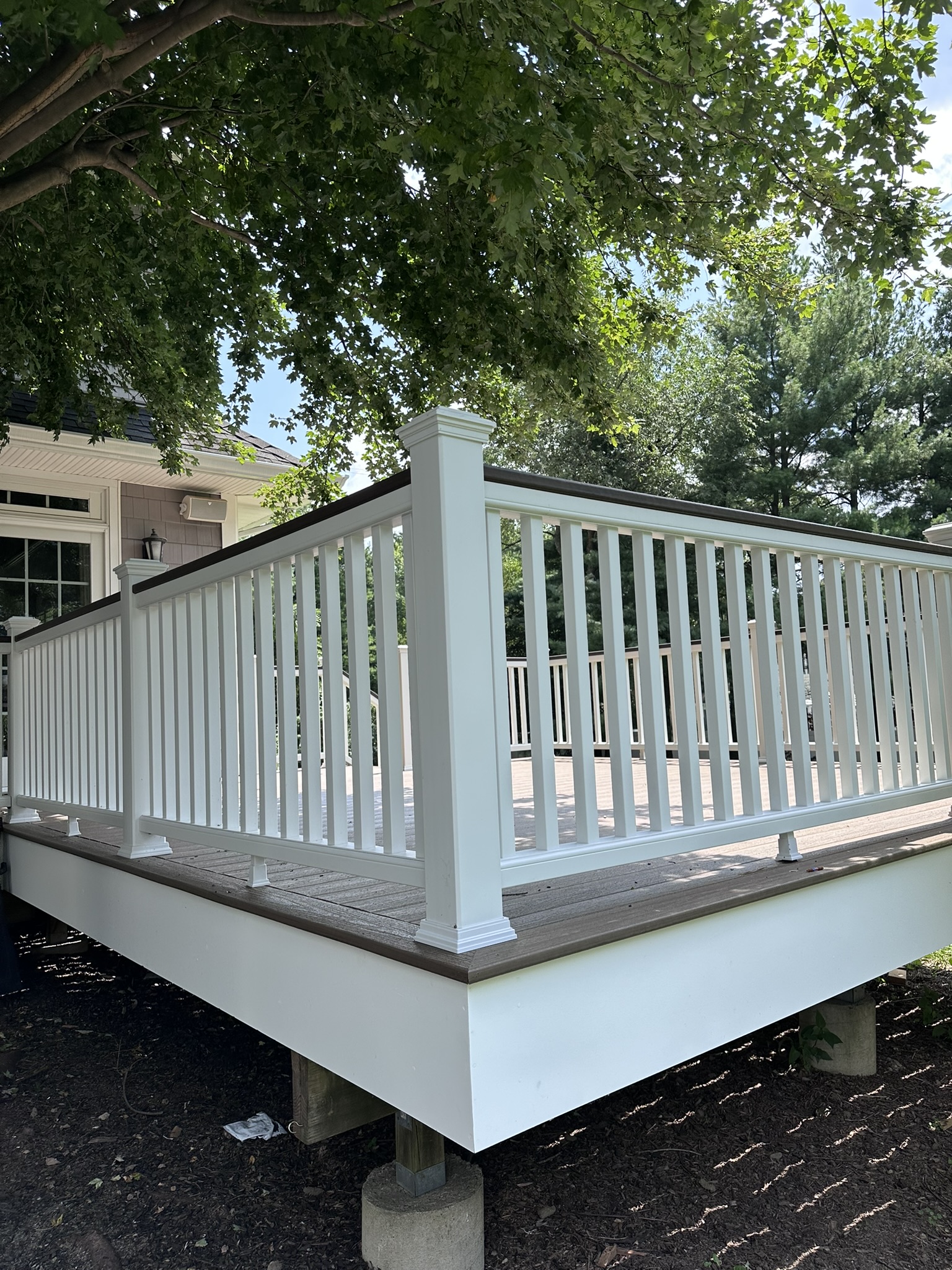 Raised composite deck in Glen Rock NJ on concrete piers with white fascia skirting
