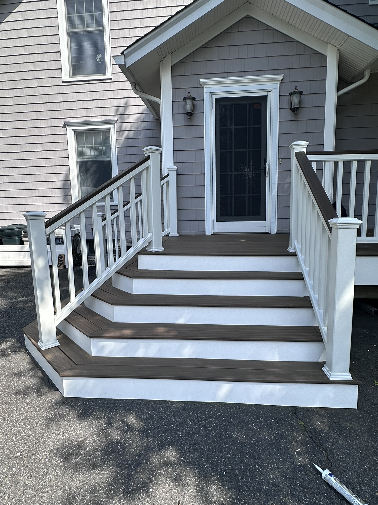 Cascading composite entry stairs in Glen Rock NJ, wrapping the corner with dark Trex treads and white risers