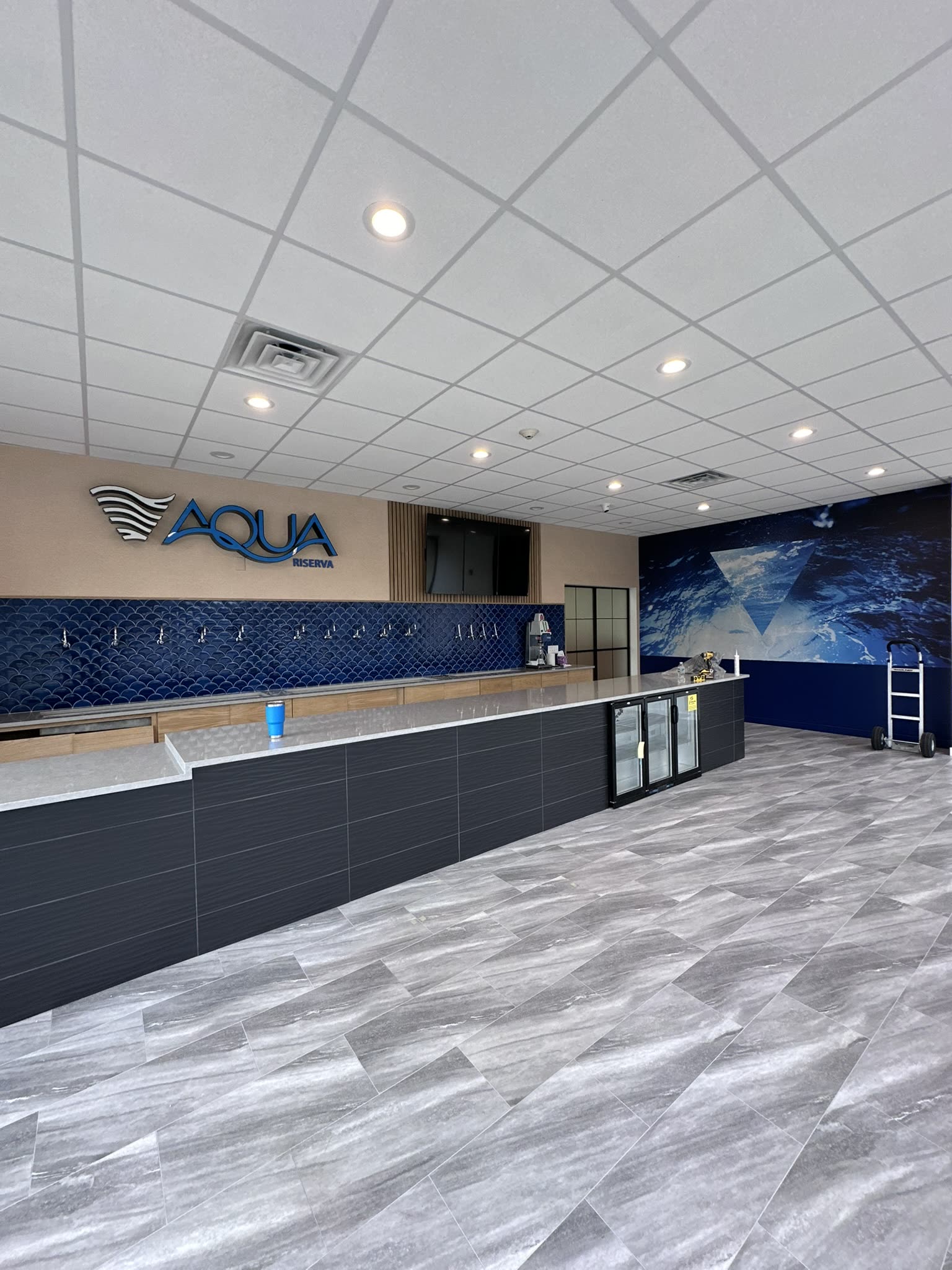 Aqua Riserva retail floor in Hawthorne NJ looking toward the counter, with the blue water mural on the far wall
