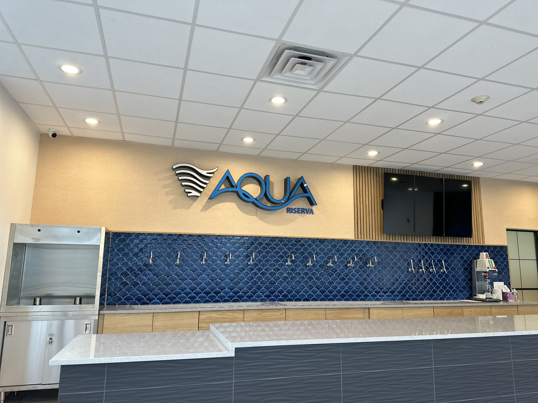 Aqua Riserva service counter in Hawthorne NJ with quartz top, dark panelled front and branded signage above