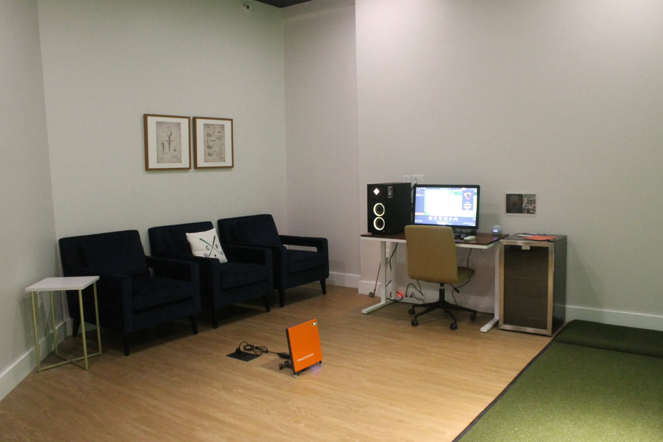 Simulator bay at Chip & Birdie&rsquo;s in Mountainside NJ with lounge seating, monitor station and the turf hitting area